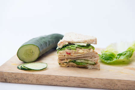 sandwich, cucumber and salad on cutting boardの写真素材