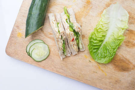 sandwich, cucumber and salad on cutting boardの写真素材