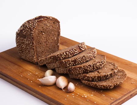 Black multigrain bread sliced with garlic on a bamboo board with sesame and sunflower seedsの写真素材