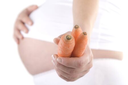 pregnant woman holding an carrot on whiteの写真素材