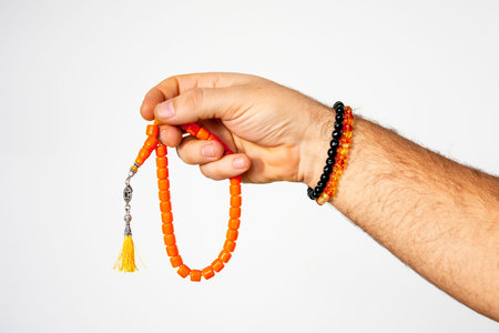 Man holding rosary made of amber in hands on isolated white background