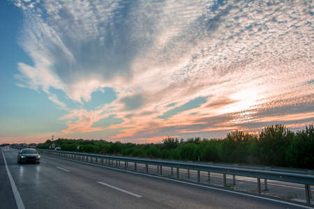 Roadside at sunset with fragmented clouds in the backgroundの写真素材