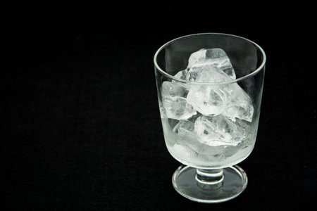 Half-filled glass with ice on a black background