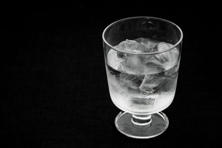 Half-filled glass with ice on a black background