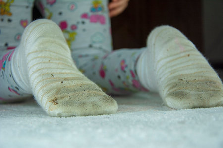 Little girl sitting on sofa in dirty socksの写真素材