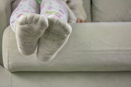 Little girl sitting on sofa in dirty socksの写真素材