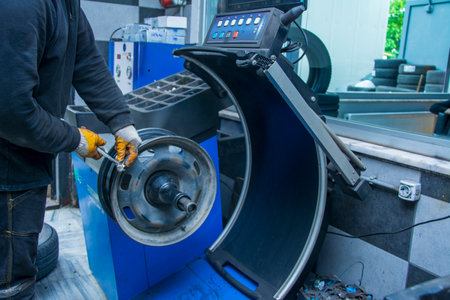 Serviceman corrects the balance of the tire rim with a piece of ironの写真素材