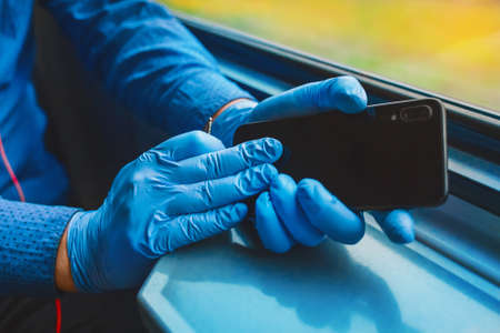 Hands of a man in protective medical gloves holding a mobile phone.の写真素材