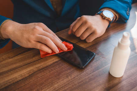 Businessman's hands wipe the phone with a napkin after using an antiseptic.の写真素材