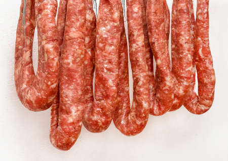 Drying pile of sausages from raw minced meat on a white wall background at home, close up.の写真素材