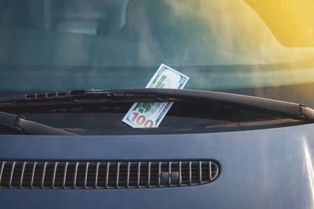100 dollars of banknotes on windshield wipers. The concept of bribery or payment of fines.の写真素材