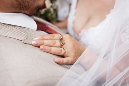 The hand of the bride with jewelry rests on the groom's shoulder close-up. Wedding decor details.