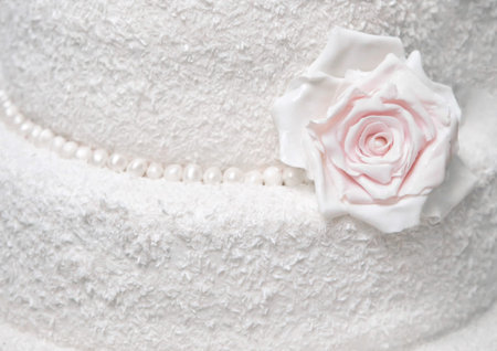 White two-tier cake with coconut shavings decorated with rose flower close up background.の写真素材