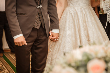 The groom in a brown suit holds the bride's hand tightly.の写真素材