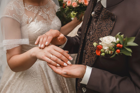 The groom's hands in a brown suit stroke and caress the bride's hands close-up.
