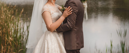 The bride put her hand on the groom's shoulder in a brown suit outdoor.の写真素材
