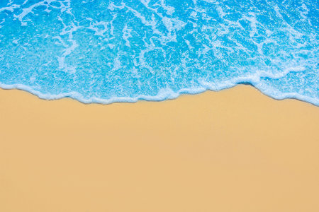 Blue sea water on light yellow beach sand.