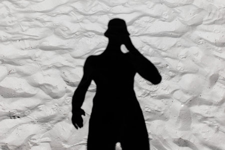 Black male silhouette shadow on white beach sand background.の写真素材