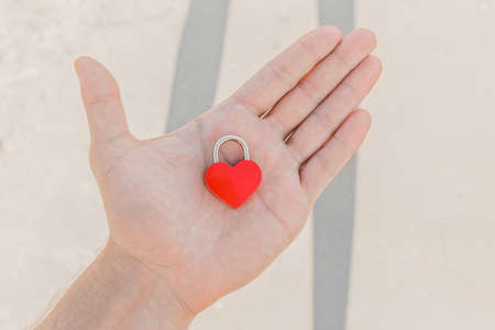 In the man's hand lies a small red heart in the form of a castle, a sign or symbol of love and romantic relationships.の写真素材