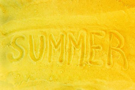 The word summer is written on a yellow beach sand background. Sign or symbol of summer concept.の写真素材