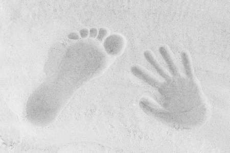 A trail from the leg and hands of a man and a woman on the white beach sand background close-up.の写真素材