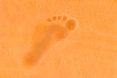 Trail from the man's foot on the orange beach sand background close-up.の写真素材