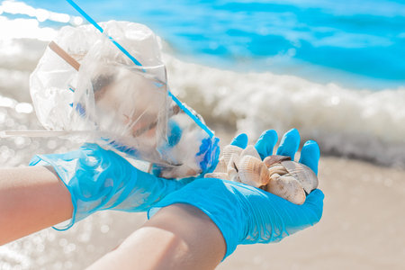 The man's hands in protective household gloves hold a bag of garbage and a pile of shells close-up....