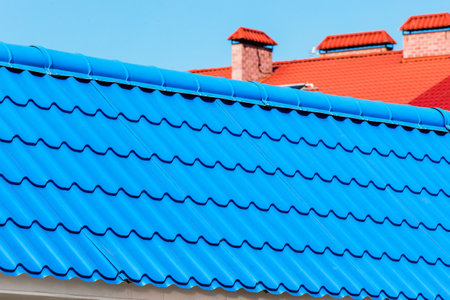 Blue tiles of the roof of a house or building against the cloud sky, close up.の写真素材