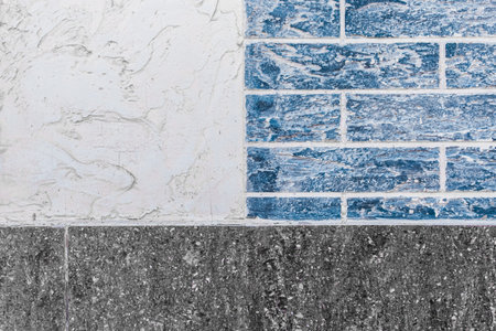 Part of modern building facade with dark black and white tiles texture and brick blue wall with abstract patterned background.の写真素材