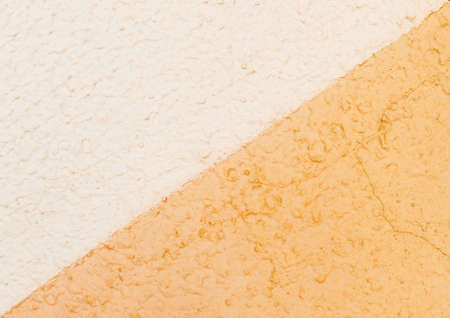 Diagonal line on a sand plaster wall with two colors - light yellow and white texture background.の写真素材