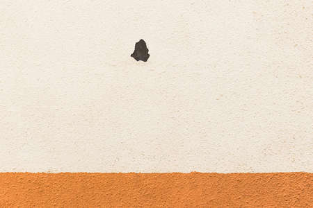 Light beige wall with a dark spot of peeling plaster texture background.の写真素材