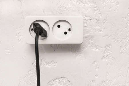 Black plug in white double socket on white plaster modern interior wall background.の写真素材
