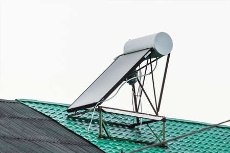 Solar water heater on the roof of a building against the background of the sky. Using solar energy to heat water.の写真素材