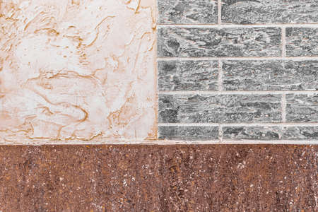 Part of modern building facade with white stucco and brown tiles texture and brick wall with abstract patterned background.の写真素材