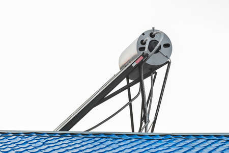 Solar water heater on the roof of a building against the background of the sky. Using solar energy to heat water.の写真素材