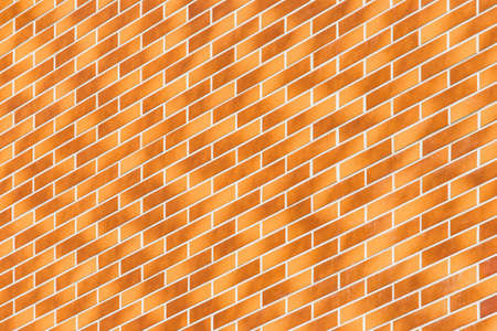 Diagonal, geometric modern light orange and brown brick wall building facade texture background.の写真素材