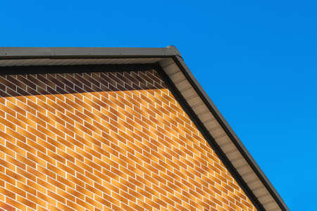 Modern house facade with brown brick wall interior against blue sky background.の写真素材