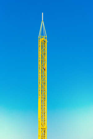 Attraction yellow tower in an amusement park against a blue sky background.の写真素材
