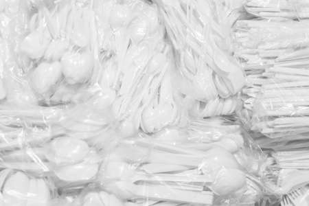 A set of white disposable plastic tableware in cellophane packaging in a store background, close up.の写真素材