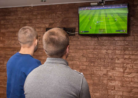 Two guys indoors playing video games and looking at the screen.の写真素材