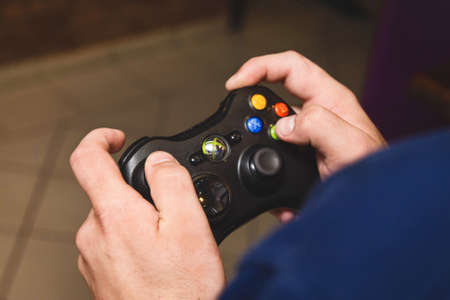 Belarus, Minsk region - August 27, 2017: The guy's hands are holding a joystick xbox and playing a console, close-up.のeditorial素材