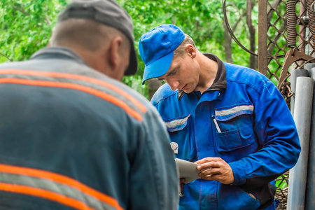 Belarus, Minsk region - July 10, 2020: Two European male gas workers check the reconciliation of gas...