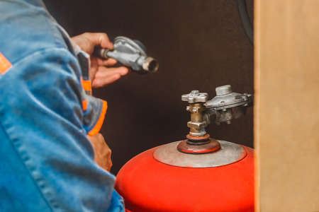 Worker man checks the connection system of the gas cylinder.の写真素材