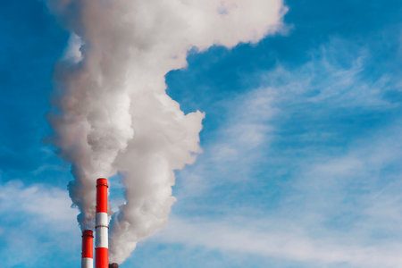 Environmental pollution, environmental problem, smoke from the chimney of an industrial plant or thermal power plant on a background of blue sky with clouds.の写真素材