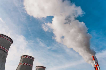 Environmental pollution, environmental problem, smoke from the chimney of an industrial plant or thermal power plant on a background of blue sky with clouds.の写真素材
