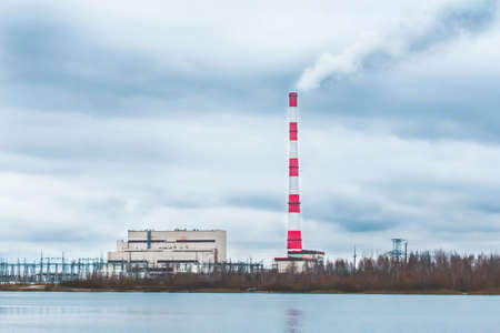 Environmental problem, environmental pollution, smoke from the pipe of an thermal power plant against a blue sky.の写真素材