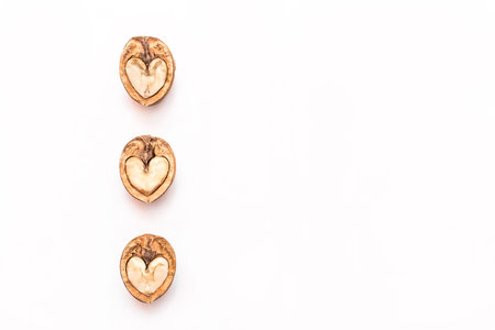 Half of the walnuts in a heart-shaped cut on a white background to copy the space.