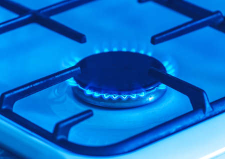 Gas burner with a blue flame on a gas stove, close-up.の写真素材