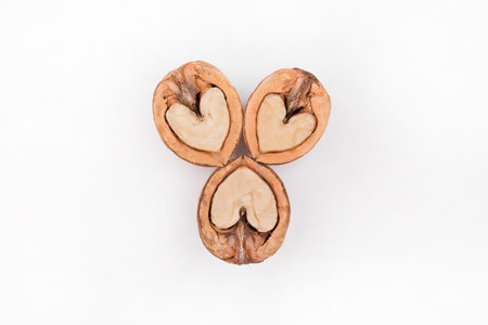 Halves of walnuts in the form of a heart isolated on white background.