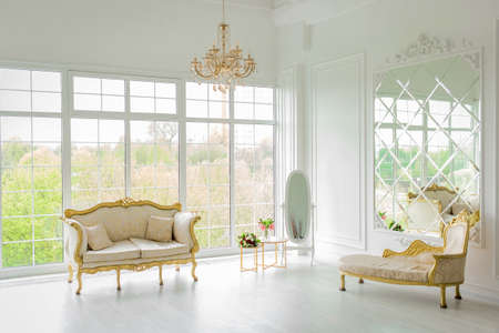 Belarus, Minsk - May 05, 2020: Furniture in a light, elegant white luxurious interior with large glass, a window and a chandelier.のeditorial素材